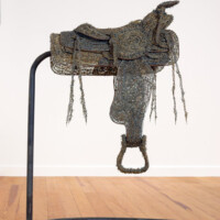 Mel Chin - Do Not Ask Me, "ROUGH RIDER" - A roping saddle made of barbed-wire focuses on the Catholic colonization of Texas. Barbed-wire, steel, 2001